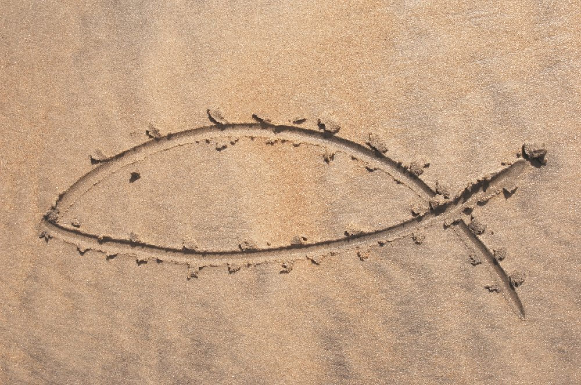 Symbole chrétien du poisson, tracé sur du sable. Vivre en disciple missionnaire